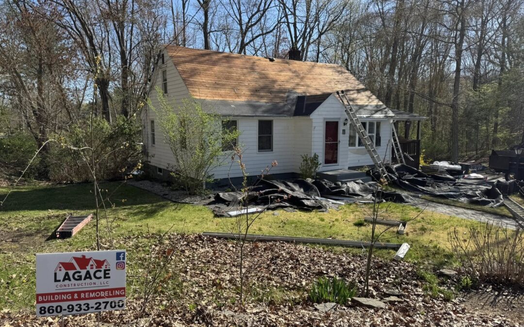 Lagace Construction replacing roof on white home in Andover, CT with visible branding sign and stripped shingles