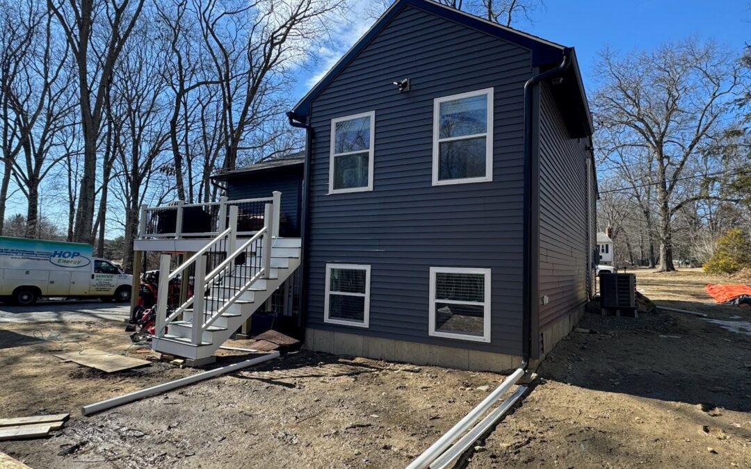 Exterior view of a custom in-law suite addition in Manchester, Connecticut, built with dark blue siding, new staircase, and lower-level windows.