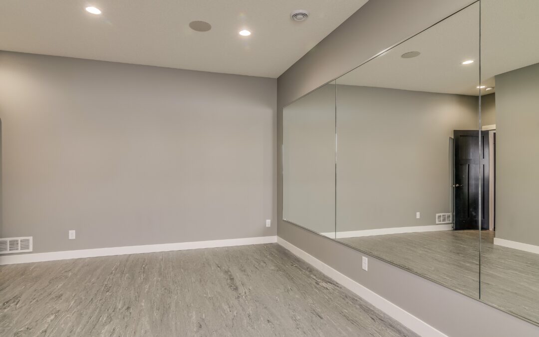 Finished basement in Tolland County CT with gray vinyl flooring, recessed lighting, and large wall mirror.